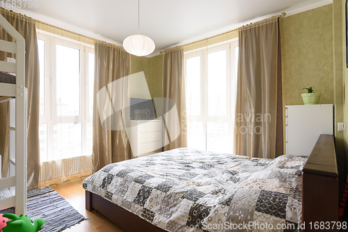 Image of Interior of a bright bedroom with a large double bed and two large stained glass windows