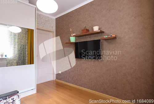 Image of The interior of a small room, a view of the wardrobe, an entrance door and a wall with a TV and shelves