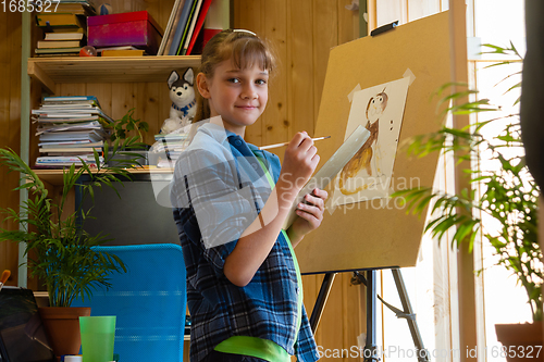 Image of The girl was distracted from drawing on the easel and looked into the frame