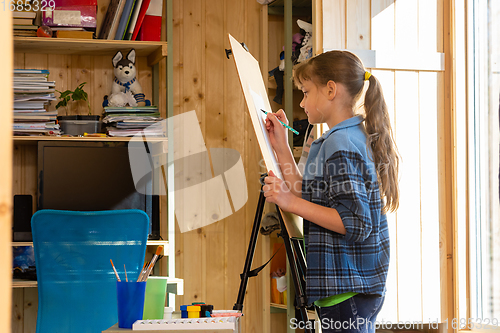 Image of A ten-year-old girl draws on an easel at home