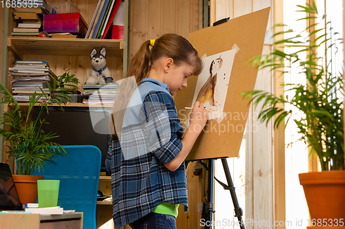 Image of Girl draws a cat on an easel in her room at home