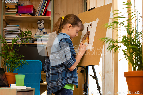 Image of Girl draws a cat on an easel in her room at home