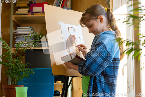 Image of A ten-year-old girl watches a video tutorial and draws a picture on a tablet