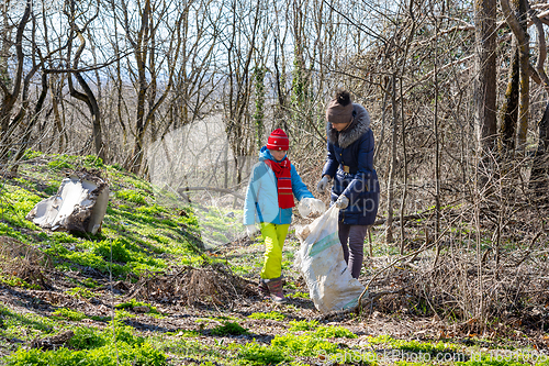 Image of Family collects trash in the forest in a big bag for recycling
