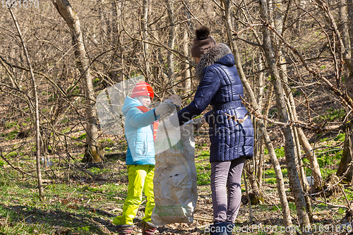 Image of A girl collects garbage in the forest, a girl holds a large garbage bag