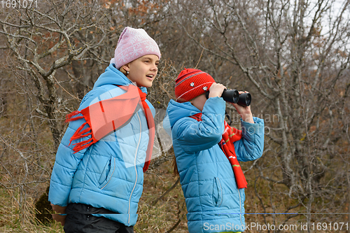 Image of Girlfriend tells another girlfriend what she saw through binoculars