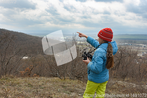 Image of The girl saw something through binoculars, looking at the mountains and points there with her finger