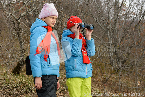 Image of The girl looks with enthusiasm through binoculars, another girl is standing nearby and looks in the same direction