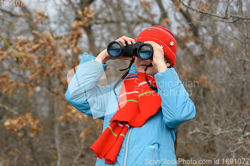 Image of Girl enthusiastically looks through binoculars, front view, close-up