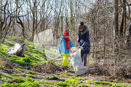 Image of Family collects trash in the forest in a big bag for recycling