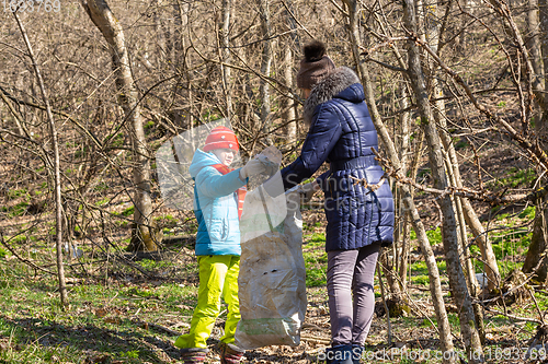 Image of A girl collects garbage in the forest, a girl holds a large garbage bag