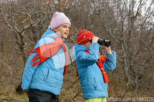 Image of Girlfriend tells another girlfriend what she saw through binoculars