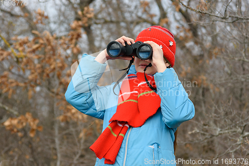 Image of Girl enthusiastically looks through binoculars, front view, close-up