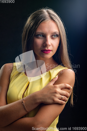 Image of Portrait of a beautiful girl in a yellow dress on a black background