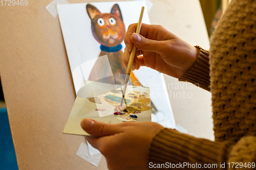 Image of Portrait of the artist at work, the hands of a girl on a palette with a brush mixes paints