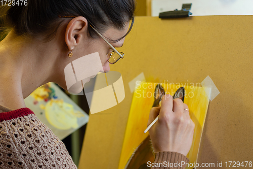 Image of The artist draws a drawing on an easel, side view, close-up