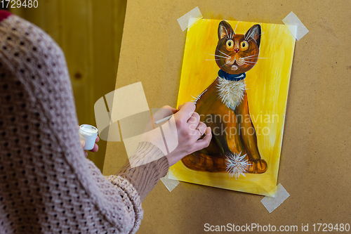 Image of The artist draws a drawing on an easel, on the artist\'s hands and a drawing