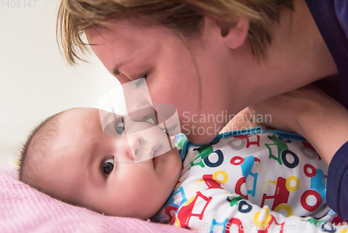 Image of young mother kissing her cute little baby