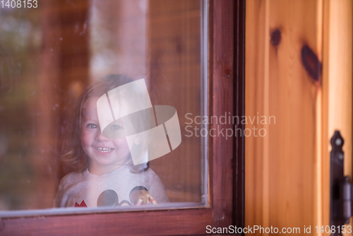 Image of little cute girl playing near the window