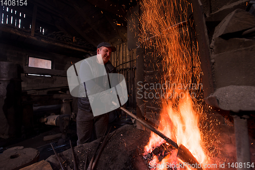 Image of young traditional Blacksmith working with open fire