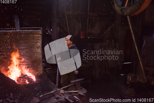 Image of young traditional Blacksmith working with open fire