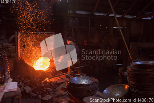 Image of blacksmith workers using mechanical hammer at workshop