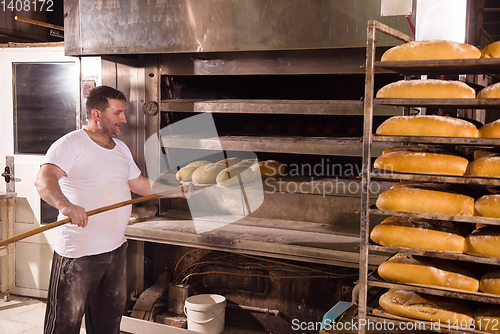 Image of bakery worker taking out freshly baked breads