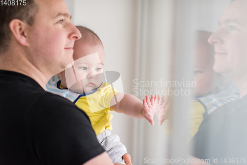 Image of young father holding baby near the window at home
