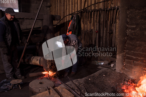 Image of blacksmith workers using mechanical hammer at workshop