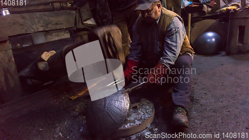 Image of blacksmith workers using mechanical hammer at workshop