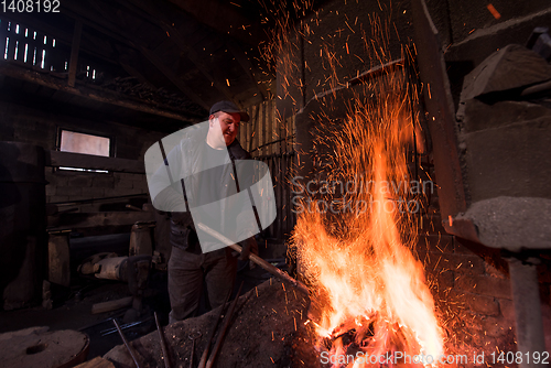 Image of young traditional Blacksmith working with open fire