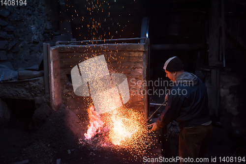 Image of young traditional Blacksmith working with open fire