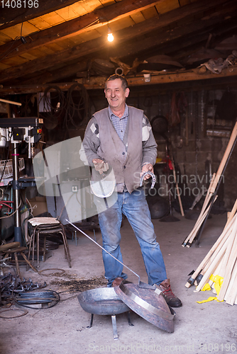 Image of A blacksmith worker showing handmade products ready for sale