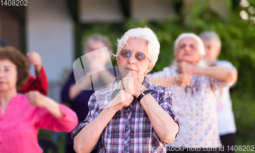 Image of senior woman exercising with friends