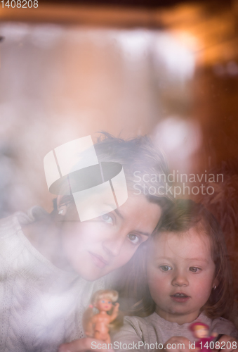 Image of young mother and little cute daughter playing near the window