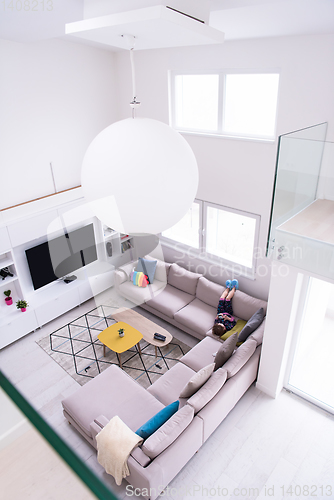 Image of little girl using a smartphone on the sofa at home