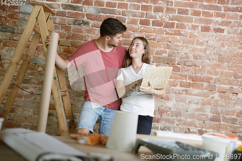 Image of Young couple doing apartment repair together themselves