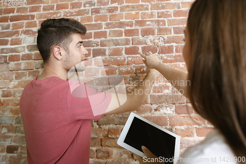 Image of Young couple doing apartment repair together themselves