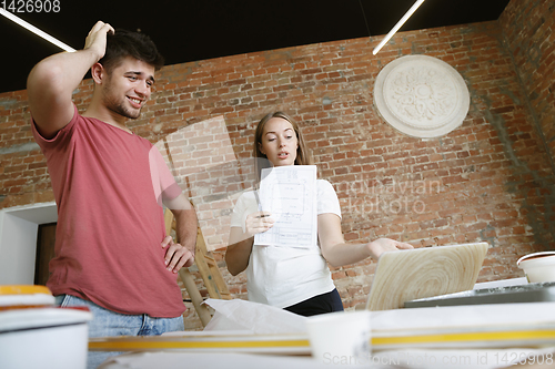 Image of Young couple doing apartment repair together themselves