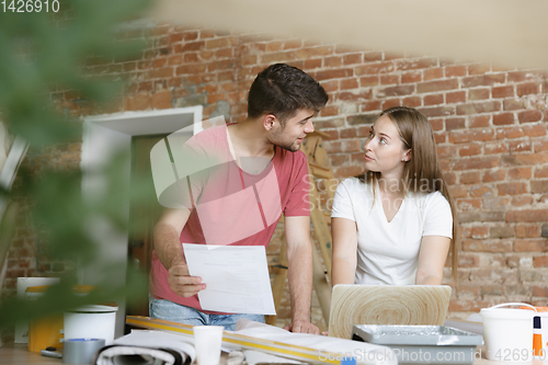 Image of Young couple doing apartment repair together themselves