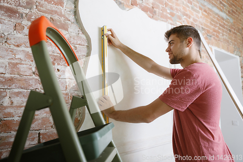 Image of Young man doing apartment repair hisselfes