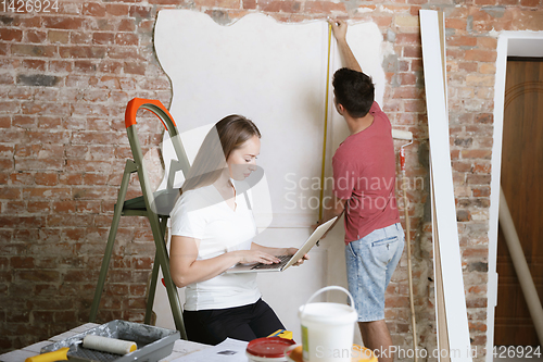 Image of Young couple doing apartment repair together themselves