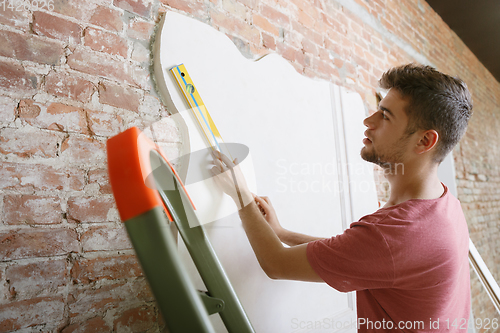 Image of Young man doing apartment repair hisselfes