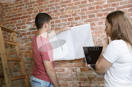 Image of Young couple doing apartment repair together themselves