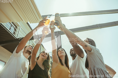 Image of Young group of friends drinking beer and celebrating together