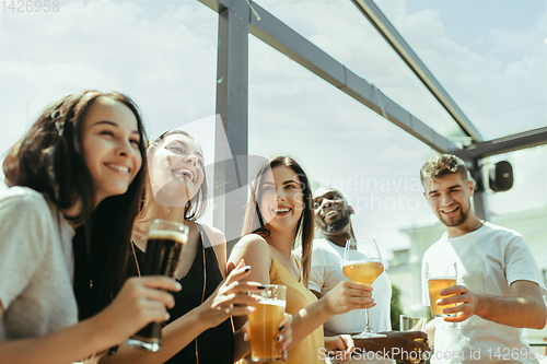 Image of Young group of friends drinking beer and celebrating together