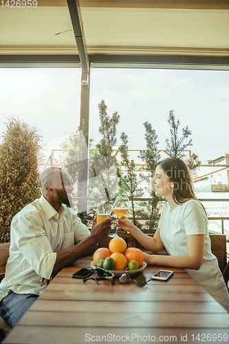 Image of Young friends or couple drinking beer and celebrating together