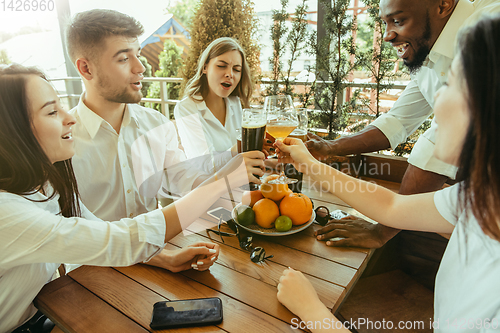 Image of Young group of friends drinking beer and celebrating together
