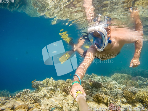 Image of man snorkel in shallow water on coral fish