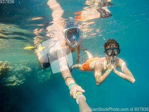 Image of father and son snorkel in shallow water on coral fish